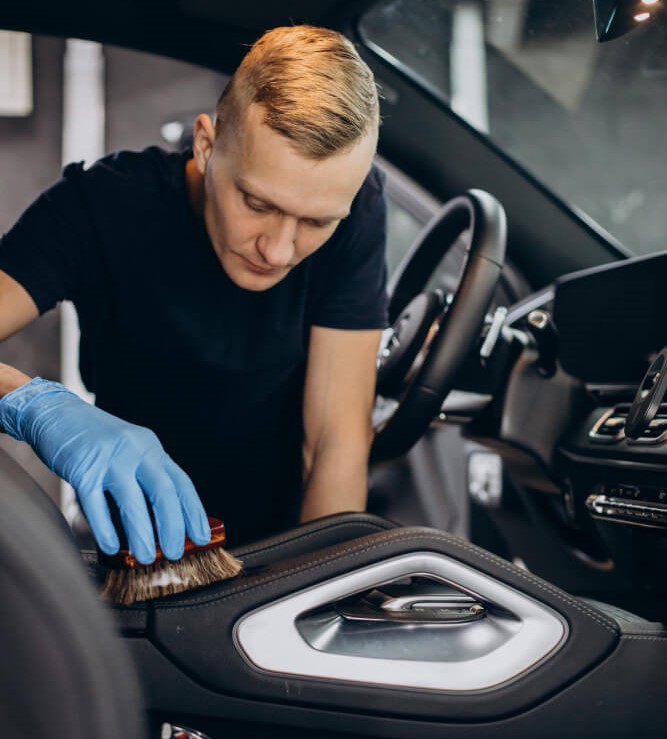 A worker cleaning the font interior of a car