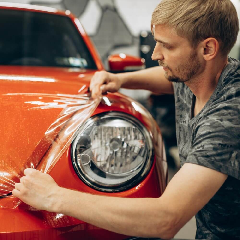 Man wrapping a car in an auto shop
