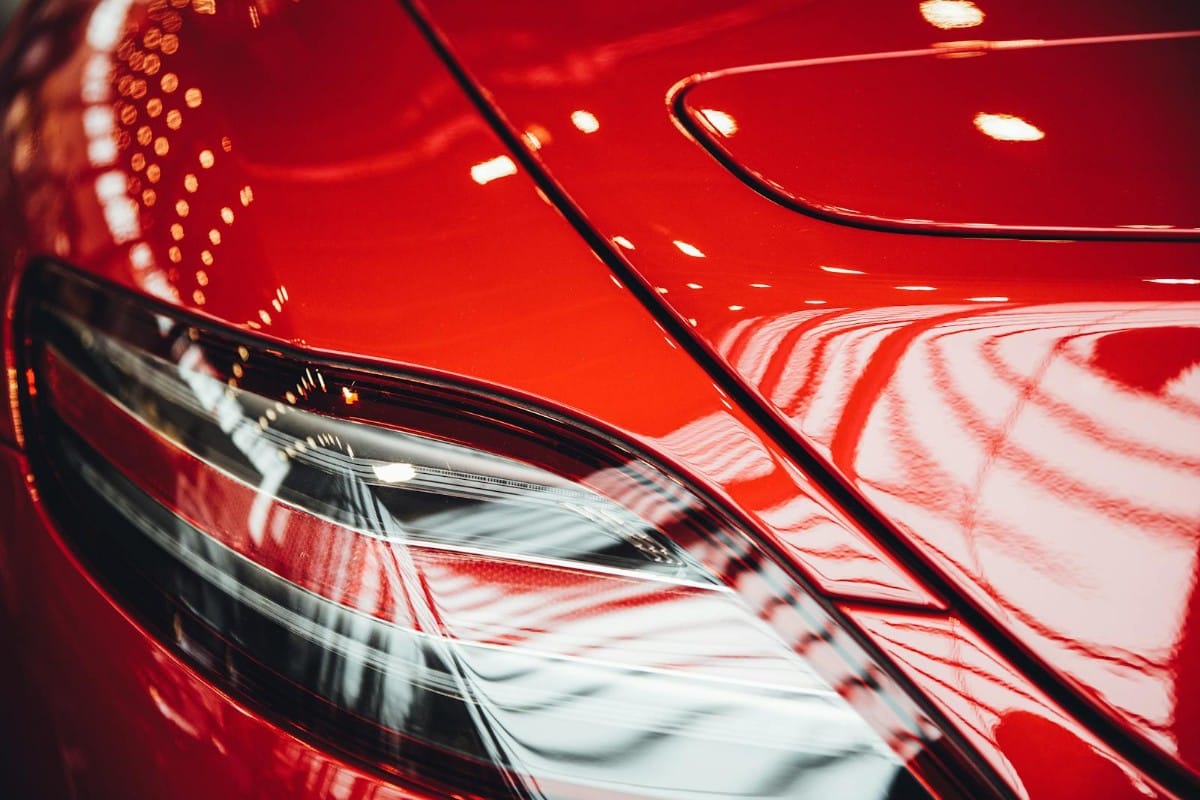 Deep red car panel with water beading on a fresh coating