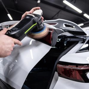 Dual-action polisher working the rear quarter panel of a white car