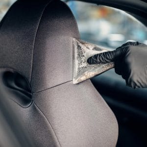Hot-water extractor nozzle drawing dirt out of a fabric car seat