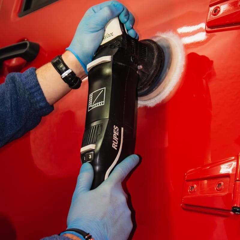 Machine polisher removing swirl marks from red paint